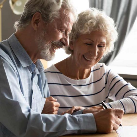 Smiling Senior Couple Signing A Life Insurance Document